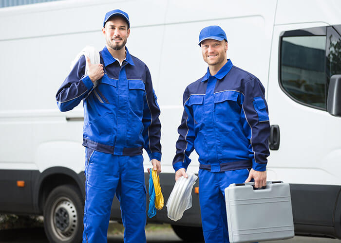 two plumbers standing in front of van